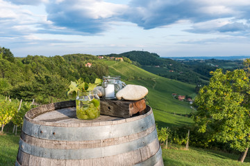 Jars with grapes and candle on wooden barrel near vineyard on south Styrian wine route