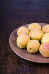 Apricots in a plate on a wooden table.