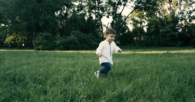 Cute baby boy with wite shirt running in grass field . Slow Motion. 4k.