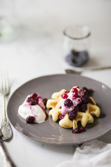 Waffle con yogurt e frutti di bosco su tavolo in marmo bianco. Prima colazione