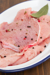 raw turkey with pepper and bay leaf on white dish