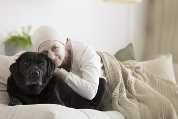 Woman with cancer hugging dog - obrazy, fototapety, plakaty