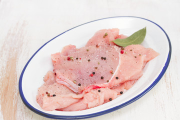 raw turkey with pepper and bay leaf on white dish