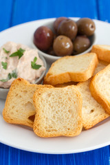 toasts with fish pate and olives on white plate