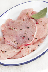 raw turkey with pepper and bay leaf on white dish