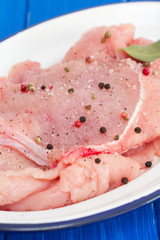 raw turkey with pepper and bay leaf on white dish