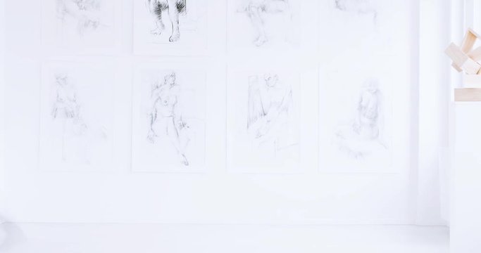 Time lap of young man with rucksack on back observing drawings while visiting art gallery with wooden sculpture
