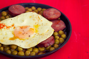 fried egg with smoked sausages and peas