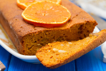 pumpkin cake with orange on white dish on wooden background