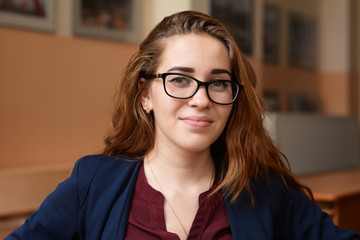 Close-up portrait of a young woman in glasses. A girl with red hair in the classroom. Business woman in training class