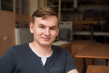 Close-up portrait of a young man. Smiling blond indoors. Student in the classroom