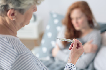 Mother looking at fever thermometer