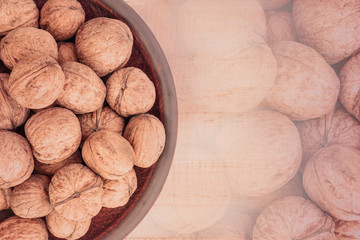 whole walnuts in a clay plate on a white wooden background. Rustic style.