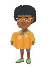 Cheerful african-american boy standing with a big orange pumpkin in hands