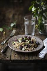 Insalata di farro con olive taggiasche, formaggio e more su tavolo rustico in legno