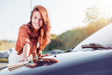 Young woman, driver, dry wiping her car with microfiber cloth