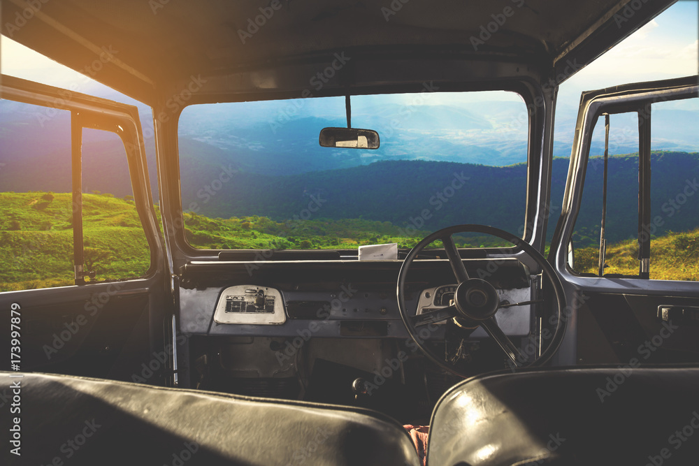 Poster view on the dashboard of the car. green forest and mountain is in front of the car.