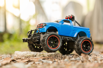 Blue RC Off-road truck car (Radio-controlled) standing on the rock and terrain sand dune. This toy has some dust from children playing. © visitr