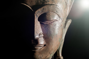 Illumination spirituelle. Tête de bouddha à la lumière divine. Visage de statue en bronze en gros plan.