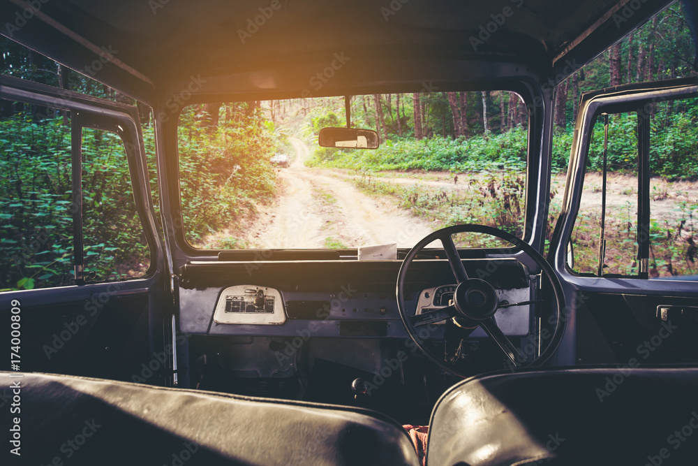 Poster view on the dashboard of the car. green forest is in front of the car.