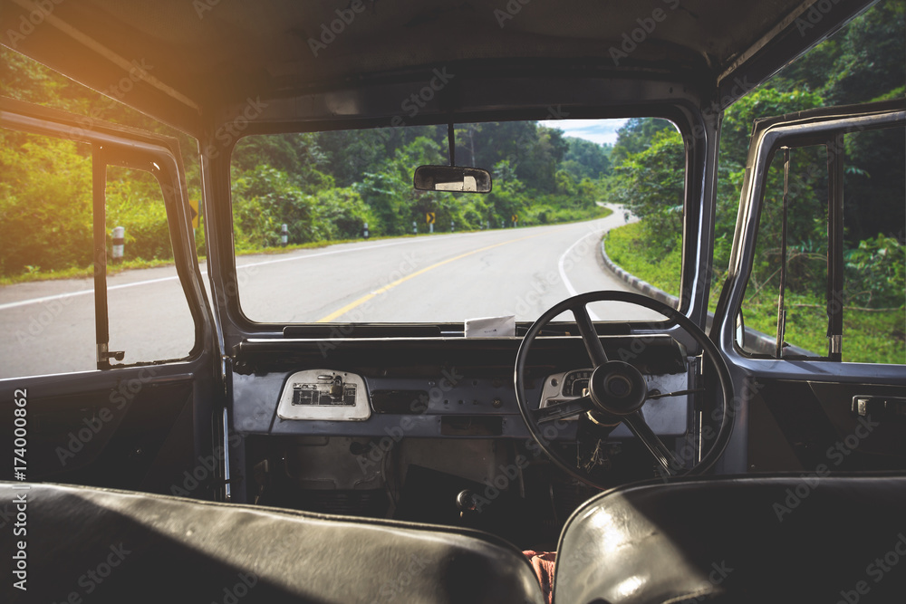 Poster view on the dashboard of the car. green forest is in front of the car.