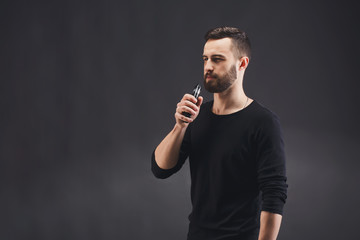 Young man vaping e-cigarette on black