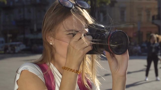 Beautiful caucasian fair hair tourist girl, with a pink backpack, is taking a photo of the Opera House and fountain in the busy, crowdy street, sunny day, slow motion