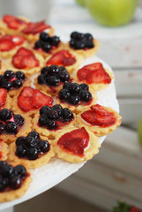 Fruit and berry tartlets dessert. Beautiful delicious tarts, bright, colorful pastry cakes sweets with fresh raspberries, figs, strawberry. French Bakery pattern.