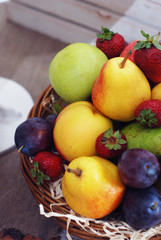 Basket of fresh organic fruits. Apples, pears, plums, strawberry.