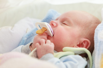 Closeup of little newborn sleeping with teat in mouth