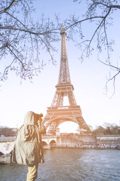 Asian male photographer in coat shooting photos while standing near Eiffel tower, Paris. France with copy space area for your text.