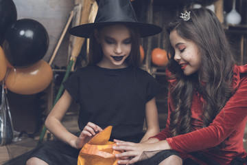 Children in Halloween costumes sit on the floor and open a pumpkin lamp for Halloween