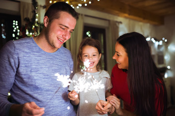 Young family with sparklers at Christmas time at home.