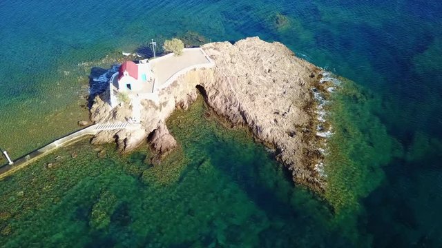 August 2017: Aerial drone video of iconic chapel of Agios Isidoros built in a rock next to the coast with clear turquoise waters, Leros island, Aegean, Dodecanese, Greece