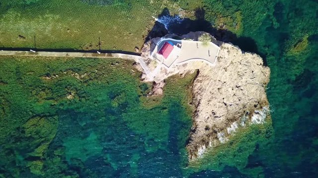 August 2017: Aerial drone video of iconic chapel of Agios Isidoros built in a rock next to the coast with clear turquoise waters, Leros island, Aegean, Dodecanese, Greece