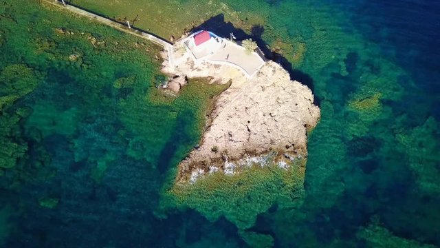 August 2017: Aerial drone video of iconic chapel of Agios Isidoros built in a rock next to the coast with clear turquoise waters, Leros island, Aegean, Dodecanese, Greece