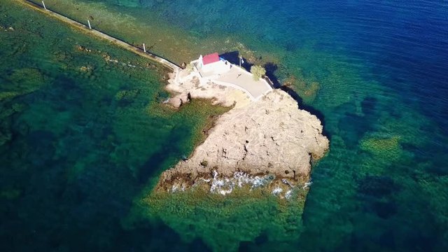 August 2017: Aerial drone video of iconic chapel of Agios Isidoros built in a rock next to the coast with clear turquoise waters, Leros island, Aegean, Dodecanese, Greece
