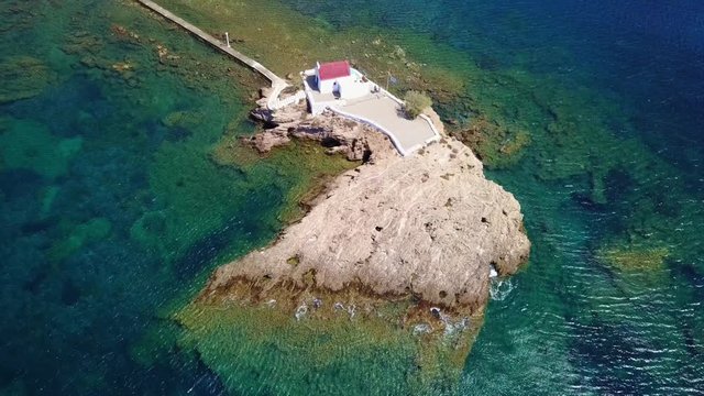 August 2017: Aerial drone video of iconic chapel of Agios Isidoros built in a rock next to the coast with clear turquoise waters, Leros island, Aegean, Dodecanese, Greece
