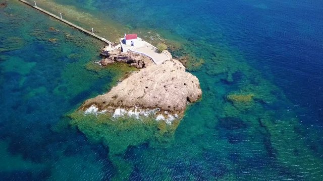 August 2017: Aerial drone video of iconic chapel of Agios Isidoros built in a rock next to the coast with clear turquoise waters, Leros island, Aegean, Dodecanese, Greece