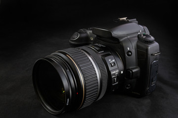 One black camera with zoom lens isolated on black background
