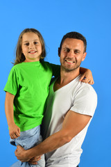 Schoolgirl sits on dads arms and smiles. Girl and man