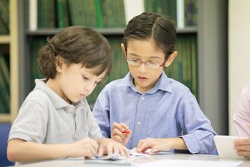 Portrait of two boy writing on paper at classroom together, Children with education concept.