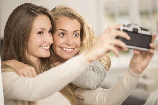 Attractive girls taking selfie picture with vintage camera