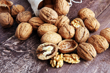 Walnut kernels and whole walnuts on rustic old wooden table.