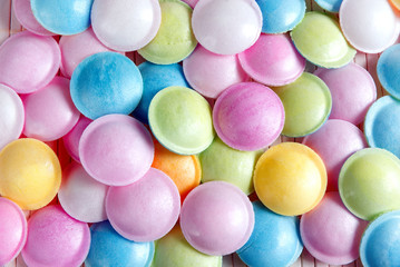 Mixed colorful candies on white wood background.Colorful lollipop and different colored round candy. Top view.