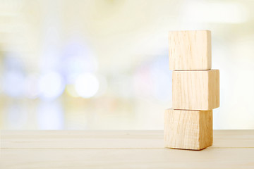 Three wooden cubes on table over blur abstract bokeh light background, banner with copy space for text