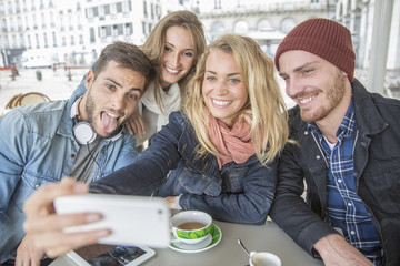 group of friends taking selfie in coffee shop