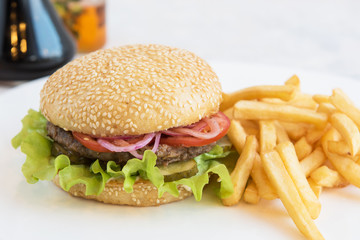 Tasty classical burger with fried potato on white table