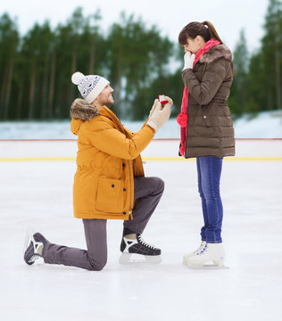 happy couple with engagement ring on skating rink
