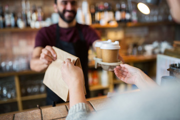 man or bartender serving customer at coffee shop